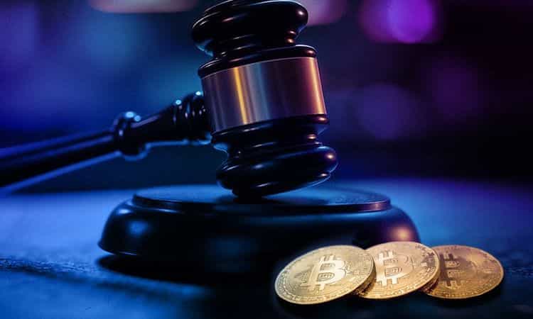 Judge's gavel beside three Bitcoin coins symbolizing cryptocurrency regulation and legal issues.